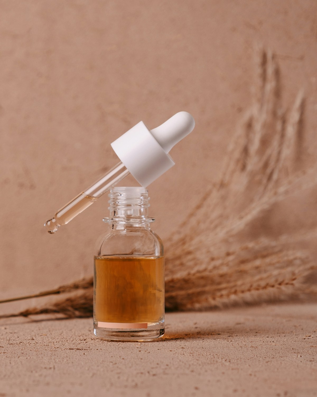 Glass bottle with dropper on a cream surface